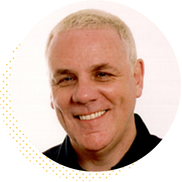 Smiling man with short blonde hair wearing a black shirt, set against a white background, conveying a friendly and approachable demeanor.