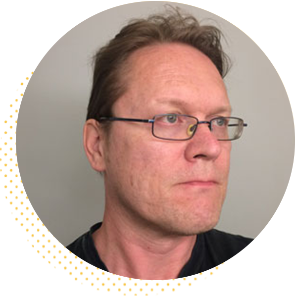 Man with glasses and short hair looking thoughtfully to the side, showcasing a neutral expression against a plain background. Ideal for profiles or professional contexts.