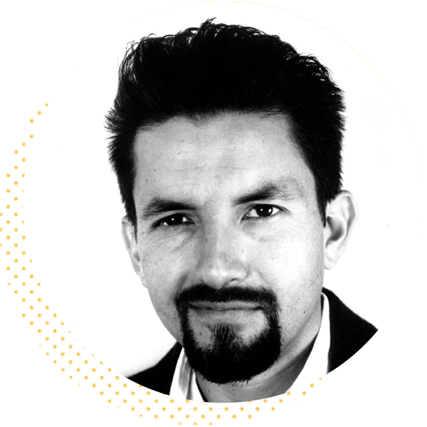Black and white portrait of a man with a goatee and styled hair, smiling confidently against a plain background.