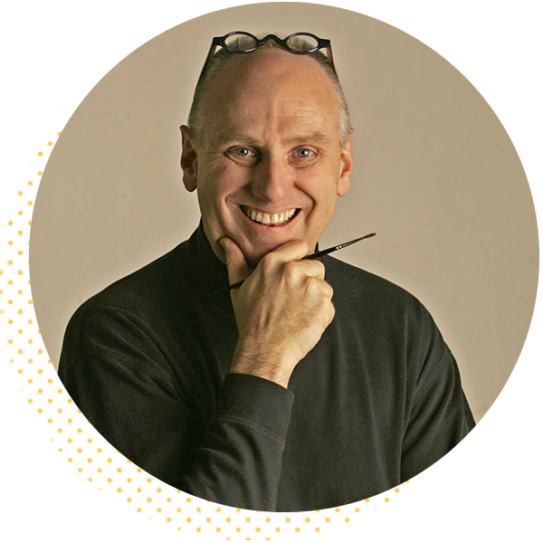Smiling man wearing a black turtleneck, holding a paintbrush and resting his chin on his hand, against a neutral background.