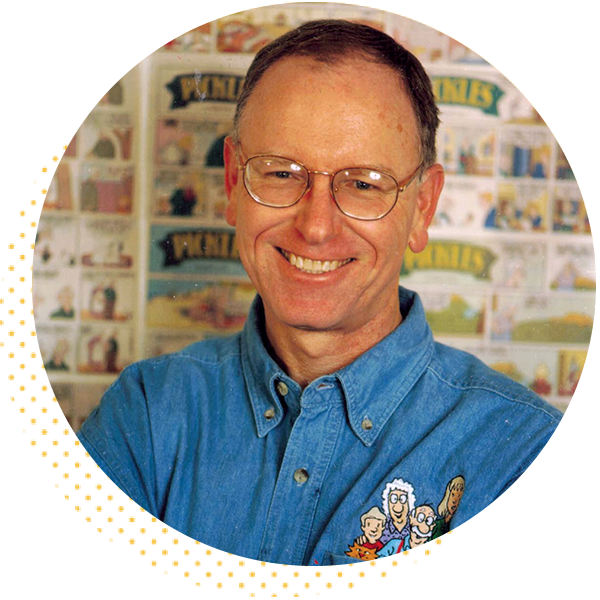 Smiling man wearing glasses and a blue shirt, standing in front of a colorful illustrated background, showcasing a creative and friendly atmosphere.