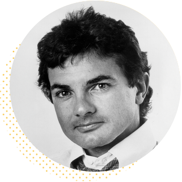 Black and white portrait of a man with tousled hair, wearing a collared shirt and tie, against a circular background. The image captures his confident expression, suitable for professional profiles or biographical content.
