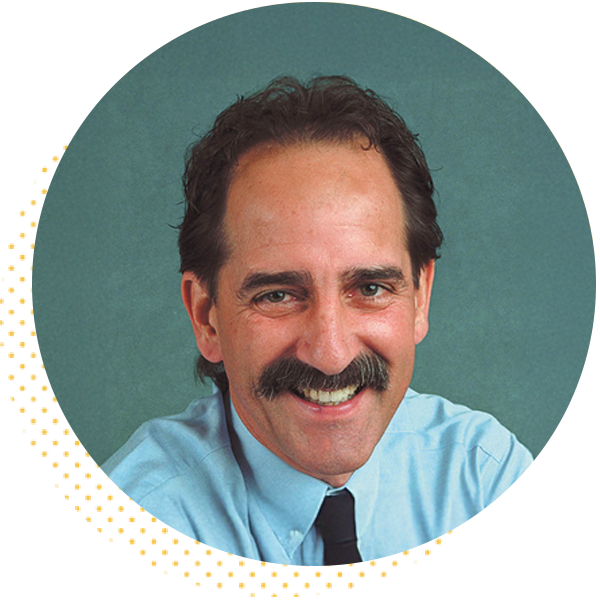 Smiling man with a thick mustache and dark hair, wearing a light blue shirt and black tie, against a teal background.