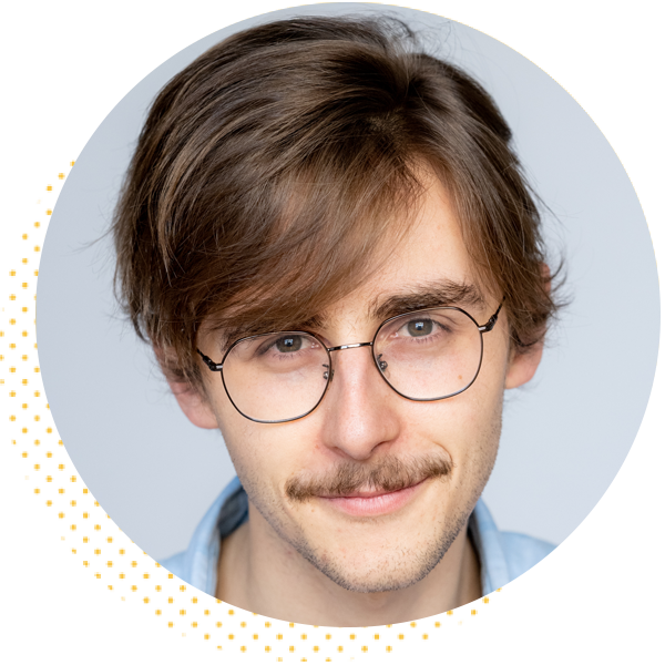 Young man with glasses and a mustache, smiling in a headshot with a light background.